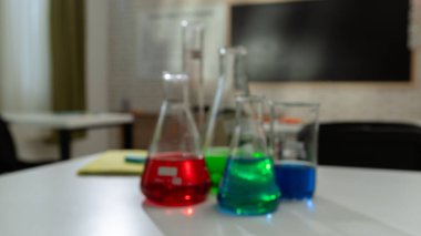 Ekipman ve mobilyalarla dolu üniversite odası. Masaları, sandalyeleri ve tahtası olan boş bir kimya sınıfı. Eğitim ve öğretim için çalışma alanı. Renkli sıvılarla dolu cam şişeler kapanıyor..
