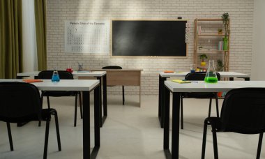 Ekipman ve mobilyalarla dolu üniversite odası. Masaları, sandalyeleri ve tahtası olan boş bir kimya sınıfı. Eğitim ve öğretim için çalışma alanı. Masaların üzerinde sıvı olan cam şişeler, ön manzara..