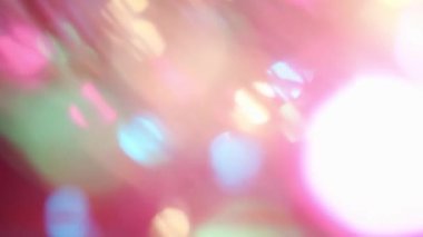 Renkli ışık sızıntısı. Bulanık renkli lensler, hareketli stüdyo yıldırımları, arka planda bokeh etkisi olan çelenkler. Işık yanıp sönüyor, soyut arkaplan görüntüleri kapanıyor.
