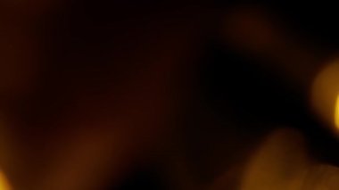 Renkli ışık sızıntısı. Bulanık altın mercek, hareketli stüdyo yıldırımı, arka planda bokeh etkisi olan çelenk. Işık yanıp sönüyor, soyut arkaplan kapanıyor.