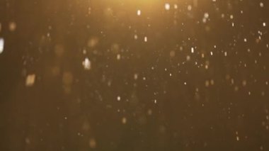Minik kıvılcımlar havada rastgele uçuşuyor, nesneler için boş uzay şablonu. Pek çok parıldayan altın parıltı, yukarıdan gelen ışıkla boş bir arkaplanda ılık bir ışıkta süzülüyor..