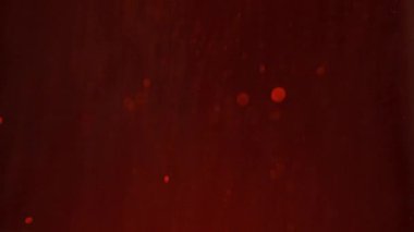 Minik kıvılcımlar havada rastgele uçuşuyor, nesneler için boş uzay şablonu. Birçok parıldayan kırmızı parıltı, yukarıdan gelen ışıkla boş koyu kırmızı arka plana düşer..