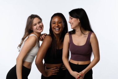 Stüdyoda bir grup çok ırklı model var. Kameraya gülümseyen, neşeli görünüşlü, beyaz stüdyo arka planında soyutlanmış üç pozitif çok ırklı genç kadın. Çok kültürlü güzellik kavramı.