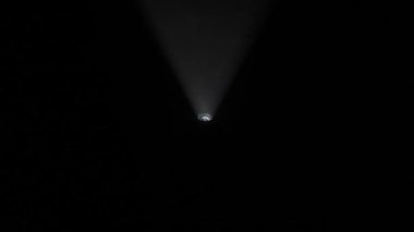 Sis stüdyosunda beyaz ışık huzmeleri. Parlak beyaz spot ışıkları profesyonel ışıklandırma ekipmanları yanıp sönüyor. Karanlıkta dönüyorlar. Duman yüzüyor, ışık yukarıdan aşağıya hareket ediyor..