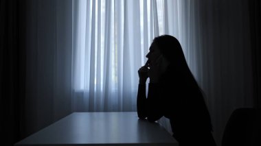 Karanlıkta odada yalnız bir kadın. Pencerenin önündeki masada oturan kadının silueti, kafası masanın üzerinde, kederli kalbi kırık bir yüz ifadesi, yalnız ve şüpheli. İnsan duyguları ve akıl sağlığı.