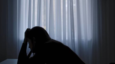 Karanlıkta odada yalnız bir kadın. Kadın silueti pencerenin önünde masada oturuyor, bitkin bir ifade, depresyon ve pişmanlık, şüphe ve umutsuzluk. İnsan duyguları ve akıl sağlığı.