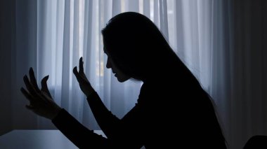 Karanlıkta odada yalnız bir kadın. Pencerenin önündeki masada oturan siluet bir kadın, kızgın somurtkan, hayal kırıklığına uğramış eller, umutsuz bir ifade. İnsan duyguları ve akıl sağlığı.