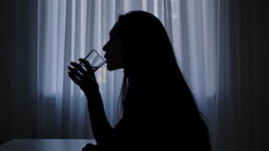Karanlıkta odada yalnız bir kadın. Pencerenin önündeki masada oturan, bir bardak su içen, şüpheyle düşünen, karar veren bir kadın silueti. İnsan duyguları ve akıl sağlığı. Yavaş çekim.