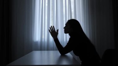 Karanlıkta odada yalnız bir kadın. Kadın silueti pencerenin önündeki masada oturuyor, pişmanlık ifadesi için yalvarıyor, üzgün üzgün ruh hali, acı çeken yorgun yüz. İnsan duyguları ve akıl sağlığı.
