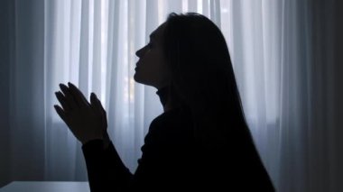 Karanlıkta odada yalnız bir kadın. Pencerenin önündeki masada oturan kadın silueti, stresi, kararsızlığı, bitkin ifadeyi, insan duygularını ve akıl sağlığını hisseder..