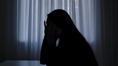 Karanlıkta odada yalnız bir kadın. Pencerenin önündeki masada oturan kadının silueti, akıllı telefondan konuşuyor, ağlama çığlıkları, dram ve kriz, kalbi kırık bir ifade. İnsan duyguları ve akıl sağlığı.