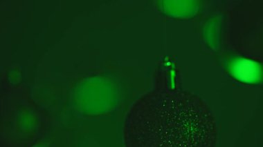 Yeni yıl dekorasyonları. Yeşil neon ışıklarıyla vurgulanmış Noel ağacı altın gümüş topları ve tepesinden sarkan duman, ışıltılı süsler yakın plan bulanık şenlik arka planında çelenkler..