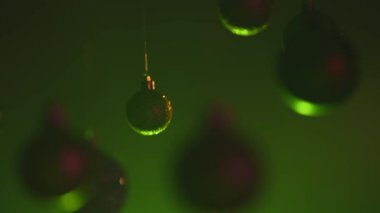 Yeni yıl dekorasyonları. Noel ağacı altın rengi toplar, tepesinden sarkan yeşil pembe neon ışıkla vurgulanmış, ışıltılı süsler, bulanık arka planda çelenkler..