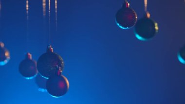 Yeni yıl dekorasyonları. Noel ağacı, altın, gümüş, yeşil toplar mavi ışıkla vurgulanmış, parlak süsler, mavi şenlik arka planında çelenkler..