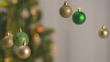 Yeni yıl dekorasyonları. Noel ağacı, altın, gümüş ve yeşil toplar, tepesinden sarkan parlak renkli oyuncaklar, şenlikli arka plana yakın çekim süsleri..