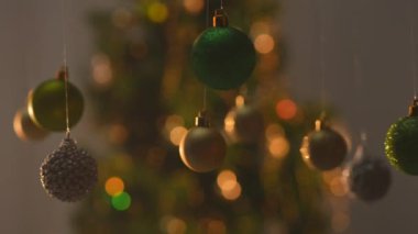 Yeni yıl dekorasyonları. Noel ağacı, altın yeşili gümüş toplar, tepesinden sarkan parlak oyuncaklar, şenlikli arka planda yakın plan süsleri..