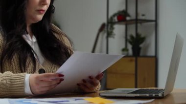 Evden uzakta bağımsız bir iş. Genç iş kadını ofis masasında uzaktan kumanda üzerinde çalışıyor, kulaklık takıyor, bilgisayardan video konuşmaları yapıyor, belgeleri okuyor. Yakın çekim.