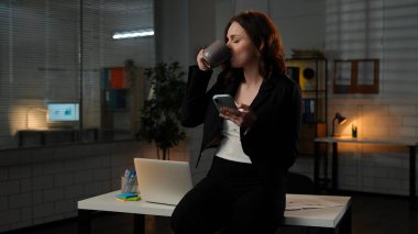 Yetişkin bölük lideri fazla mesai yapıyor. Genç iş kadını gece geç saatlere kadar masabaşında çalışıyor. Akıllı telefondan kahve içiyor. Rahatlamış bir ifade takınıyor..