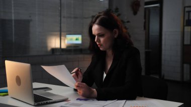 Ofiste çalışan bir iş adamı. Genç iş kadını geç saatlere kadar masa başında çalışır, dizüstü bilgisayar kullanır, belgeler okur, kafası karışan ciddi ifadeler, yan çekimler....