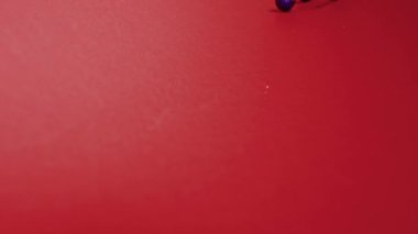 Yeni yıl dekorasyonları. Noel ağacı mavi ve altın parıltılı toplar, yukarıdan düşen renkli oyuncaklar, kırmızı arka planda kıvrılıp yuvarlanıyorlar..