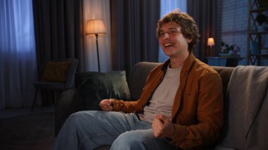 Adam evde boş vakit geçiriyor. Genç bir adam akşamını evde, kanepede oturarak TV 'de spor maçı izleyerek, mutlu bir ifadeyle, güzel bir jestle geçirir..