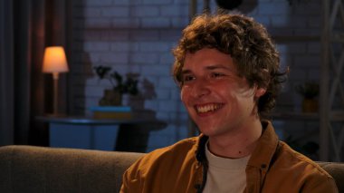 Adam evde boş vakit geçiriyor. Genç bir adam akşamını evde, oturma odasında kanepede oturup televizyon izleyerek, film ya da haber programlarıyla, olumlu gülücükler atarak, kapatarak geçirir..