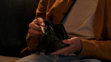 Adam evde boş vakit geçiriyor. Genç bir adam geceyi evde, kanepede, oturma odasında oturarak geçirir. Cüzdanını açar ve içinde para arar. Cüzdanı sallar..