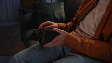 Adam evde boş vakit geçiriyor. Genç bir adam akşamını evde, kanepede oturarak geçirir. Oturma odasında, cüzdanı açar. Nakit para çıkarır, banknotları sayar, yan çekimler yapar..