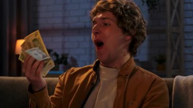 Adam evde boş vakit geçiriyor. Genç bir adam geceyi evde, kanepede oturarak, cüzdanını tutarak ve para çekerek geçirir..