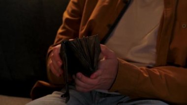 Adam evde boş vakit geçiriyor. Genç bir adam geceyi evde, kanepede oturarak geçirir. Oturma odasında, cüzdanı açar, nakit para çıkarır, banknotları sayar, faturaları içine koyar, yakın çekim yapar..