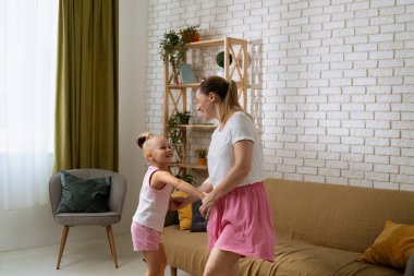 Mutlu bir anne ve küçük bir kız çocuğu. Genç anne ve kız evde birlikte vakit geçiriyorlar, el ele tutuşuyorlar gülümsüyorlar, olumlu ifade ediyorlar, orta atış yapıyorlar..