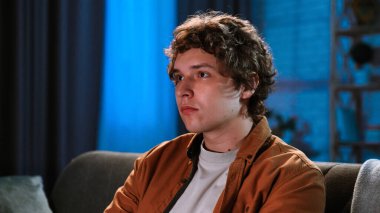 Adam evde boş vakit geçiriyor. Genç adam akşamını evde, oturma odasında kanepede oturup televizyon izleyerek, film ya da haber programlarıyla, odaklanmış ifadeyle, kapatarak geçirir..