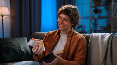 Adam evde boş vakit geçiriyor. Genç adam akşamını evde, kanepede oturarak, cüzdanını ve para fanatiğini tutarak geçiriyor. Nakit, mutlu bir ifade, kapat..