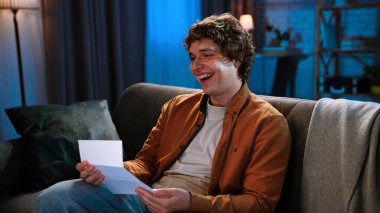 Adam evde boş vakit geçiriyor. Genç adam geceyi evde, oturma odasında koltukta oturup, kira faturasını mutlu bir yüzle okuyarak, gülümseyerek, kapatarak geçirir..