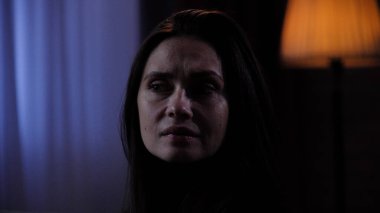 Karanlık dairede depresif bir kadın. Ruhsal sorunları olan bir kadın silueti, koltukta oturuyor, depresif bir ifade, etrafına bakıyor, ilgisiz melankolik bir yüz, yakın çekim.