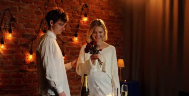 Evlilik teklifi konsepti. Sevgililer Günü 'nü kutlayan ve restoranda romantik bir akşam yemeği yiyen bir çift. Masada elinde çiçeklerle bekleyen bir kadın ve erkek. Kırmızı güller..