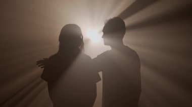 El hareketleri ve işaretleri. Stüdyonun arka planında izole edilmiş, parlak renkli spot ışıklarının karşısında sarılıp yürüyen kadın ve erkeğin siluetleri..