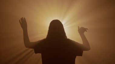 El hareketleri ve işaretleri. Kadın silueti elleriyle hassas bir şekilde dans ediyor, kollarını yavaşça parlak altın renkli spot ışıklarına doğru hareket ettiriyor, stüdyo arka planında izole edilmiş..