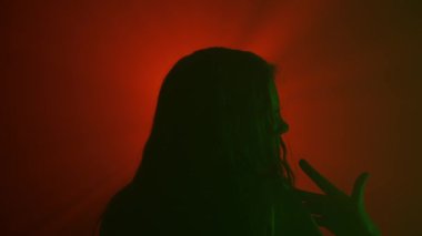 El hareketleri ve işaretleri. Kadın yeşil neon renkli siluet dans ediyor ve hareket ediyor, parlak kırmızı spot ışıklarının karşısında dans ediyor ve kuduruyor, stüdyo arka planında izole edilmiş..
