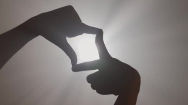 El hareketleri ve işaretleri. El silueti, resim çerçevesi yapan kişi, parlak renkli spot ışıklarına işaret veriyor, stüdyo arka planında izole edilmiş, yakın plan çekimi..