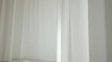 Evde şeffaf tül perdeleri olan pencereler. Şeffaf beyaz ipekten yumuşak kumaşlar güneş ışığı altında yüzüyor, gölgeler tekstil yüzeyine yansıyor..