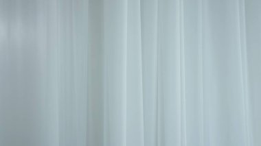 Evde şeffaf tül perdeleri olan pencereler. Şeffaf beyaz ipekten yumuşak kumaşlar güneş ışığı altında yüzüyor, gölgeler tekstil yüzeyine yansıyor, kapanıyor..