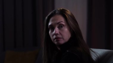 Karanlık dairede depresif bir kadın. Akıl sağlığıyla ilgili sorunları olan bir kadın, battaniyeyle kaplı bir kanepede oturuyor, depresif bir ifade, kendi kendine konuşuyor, deliriyor, kapatıyor..