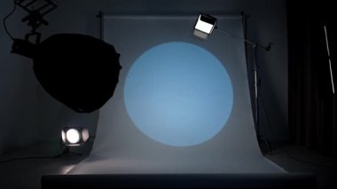 Profesyonel bir stüdyonun içinde. Modern ışıklandırma ekipmanlarıyla fotoğraf ve video çekimi için profesyonel stüdyo, büyük beyaz siklonama arka planı, renkli spot ışığı filtreleri test etme.