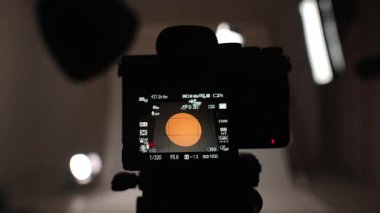 Profesyonel bir stüdyonun içinde. Işıklandırmalı ve büyük siklonama arkaplanlı profesyonel video çekim stüdyosu, canlı görüntüleme ekranlı ve canlı kayıt yapan üç ayaklı kameradan pov.