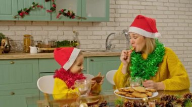 Her gün aile hayatı. Anne ve kızı Noel mutfağında süslenmiş, anne kıza zencefilli kurabiye yapmayı öğretiyor, anne ve kız Noel Baba şapkası takıyor ve kakao içiyor..