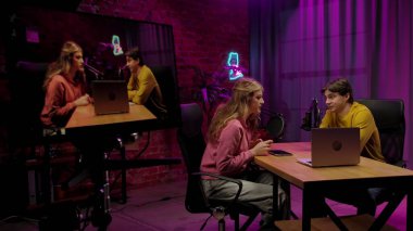 Çevrimiçi yayın. Ev sahibi ve konuk kayıt röportajının sahne arkası podcast stüdyosunda dijital içerik, sunucu ve kadın sohbeti dizüstü bilgisayarda, video akışı ile yan yana..