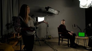 Çevrimiçi podcast gösterisi. Sahne arkası sunucusu ve konuk kayıt stüdyosunda dijital içerik yaratma, yapımcı sunucu ve kadınla konuşma, masadaki dizüstü kroma anahtar yeşil ekran.