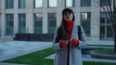 Sonbahar kıyafetleri içinde şık bir kadın şehir sokaklarında yürüyor. Telefonuyla navigatörle doğru yolu bulmaya çalışan bir kadın büyük bir binanın yakınındaki şehir merkezinde. Etkin yaşam tarzı kavramı.