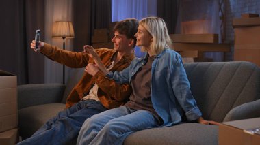 Genç bir adam ve bir kadın oturma odasında bir taşınma partisi hakkında konuşuyorlar. Birbirine aşık bir çift kanepeye oturur ve ev şeklinde anahtarlıklarla kendi fotoğraflarını çekerler..